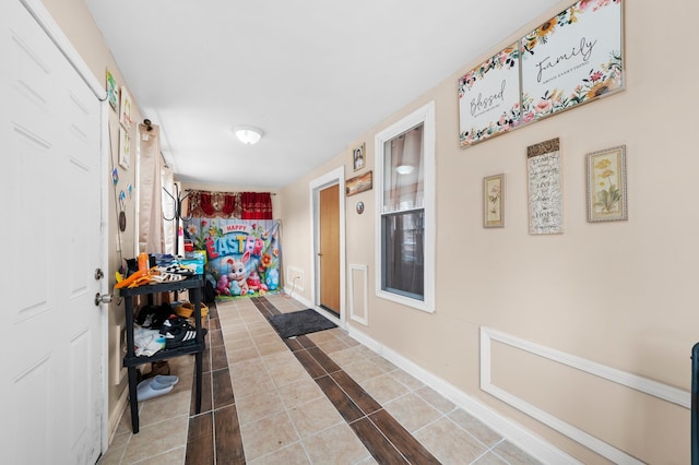 hallway featuring baseboards and tile patterned floors