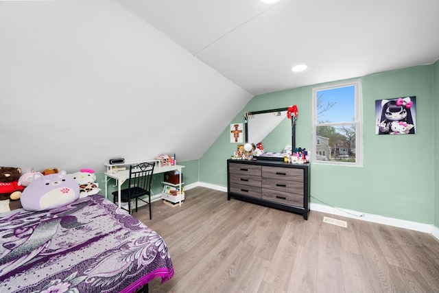 bedroom with baseboards, visible vents, wood finished floors, and lofted ceiling