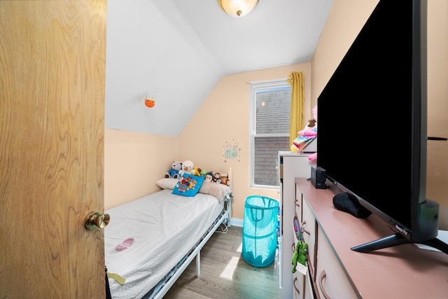 bedroom with baseboards, vaulted ceiling, and wood finished floors