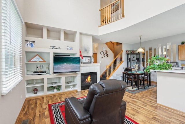 143 Foxglove Unit 143, Romeoville, IL 60446 - living area with light wood-style flooring, stairs, baseboards, a tile fireplace, and a high ceiling