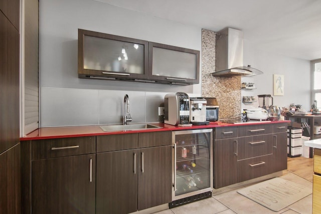 kitchen with decorative backsplash, wine cooler, glass insert cabinets, wall chimney exhaust hood, and a sink