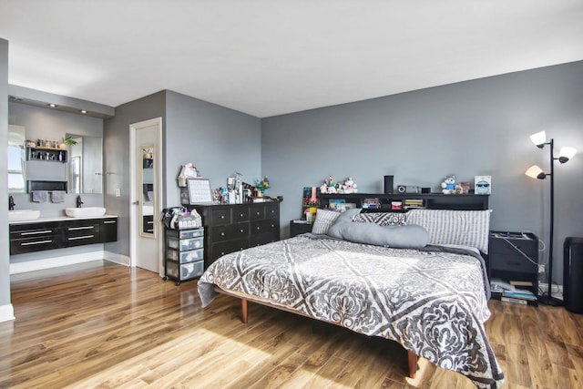 bedroom featuring baseboards, a sink, and wood finished floors