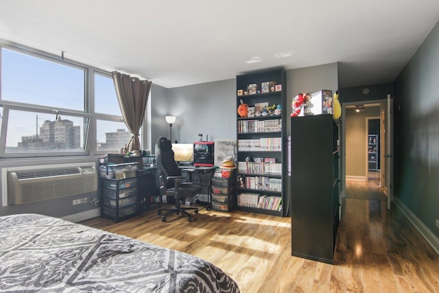 bedroom featuring a wall unit AC and wood finished floors