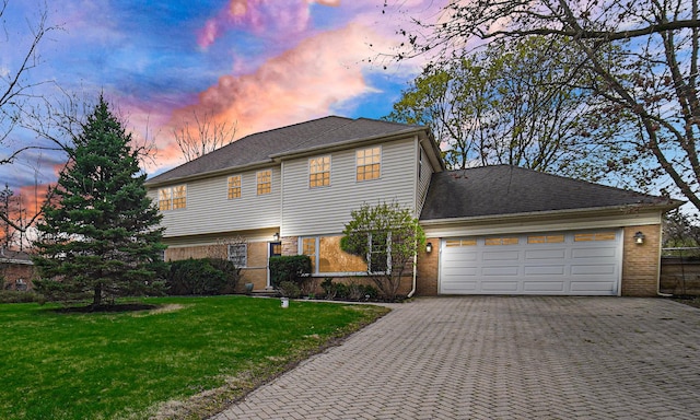view of front of home with a yard, brick siding, an attached garage, and decorative driveway