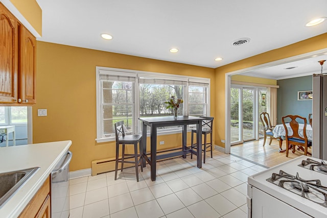 kitchen with brown cabinets, dishwasher, a sink, baseboards, and white range with gas cooktop