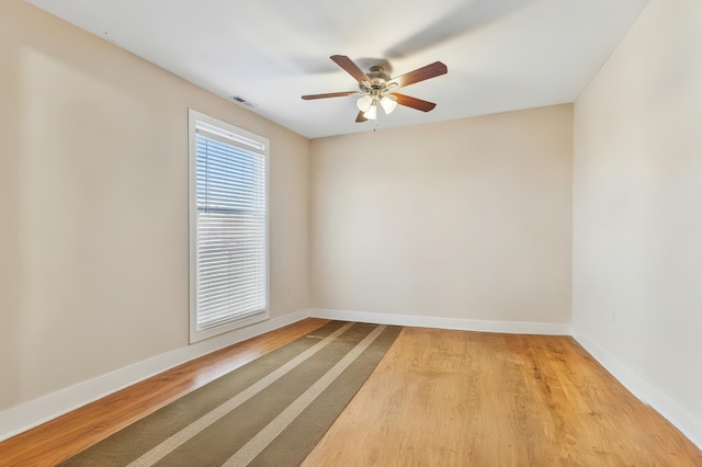 spare room with light wood-style floors, baseboards, a ceiling fan, and visible vents
