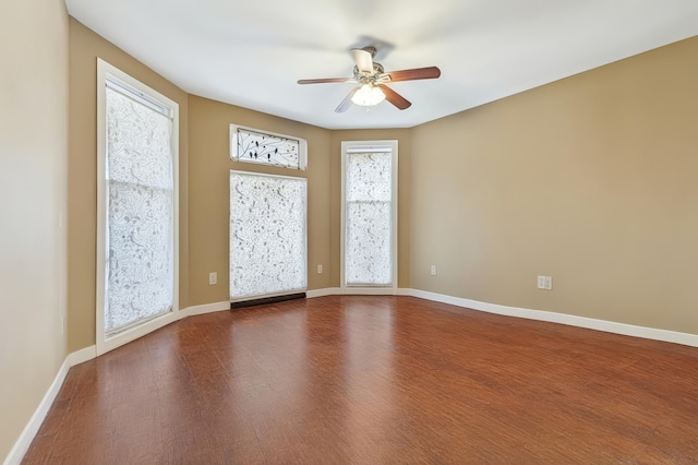 spare room featuring baseboards, ceiling fan, and wood finished floors
