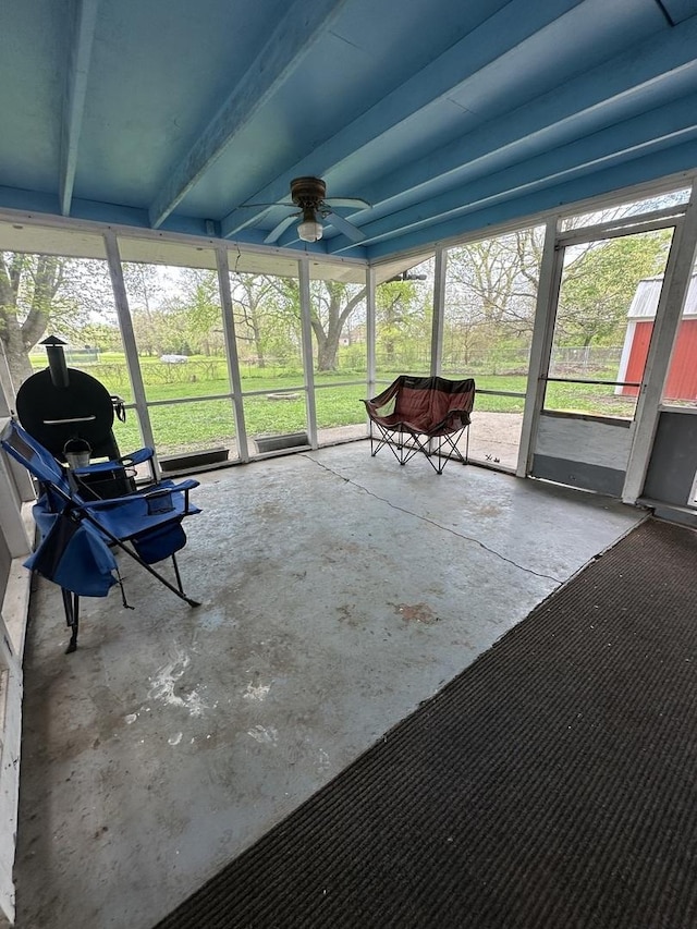 sunroom featuring a ceiling fan and beam ceiling