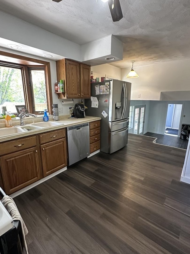 kitchen with stainless steel appliances, ceiling fan, brown cabinetry, and a sink