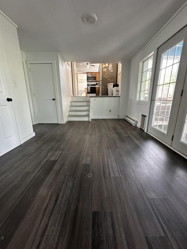 unfurnished living room with ceiling fan, dark wood finished floors, baseboard heating, and stairway