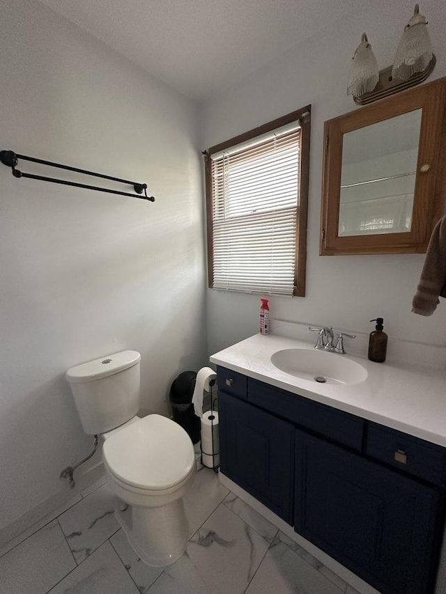 bathroom with vanity, toilet, and marble finish floor