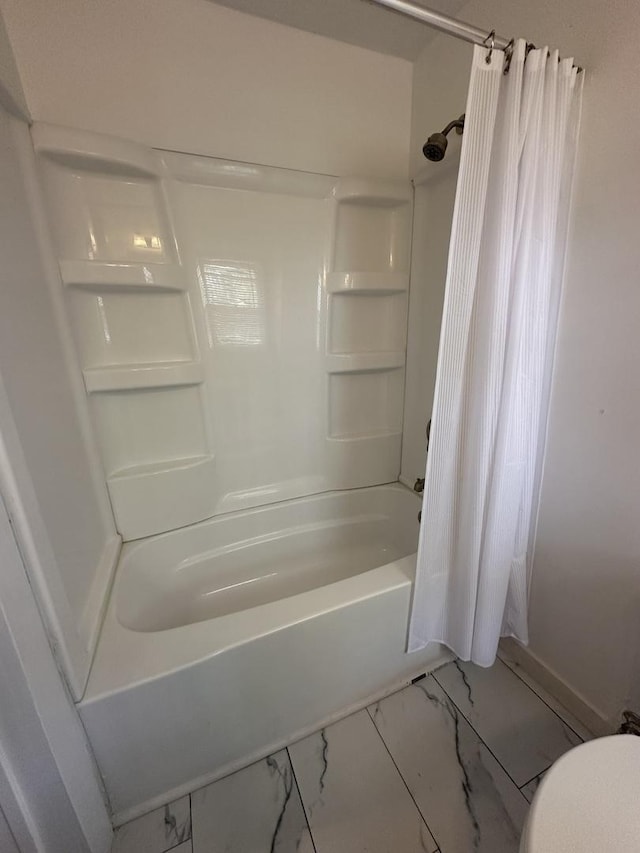 full bathroom featuring baseboards, marble finish floor, and shower / tub combo