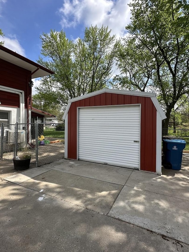 detached garage featuring fence and concrete driveway