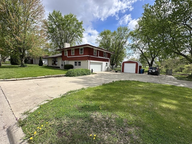 split level home with an outbuilding, driveway, a chimney, and a front lawn