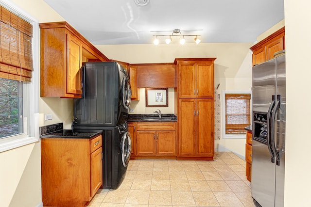1208 Main St, Crete, IL 60417 - kitchen featuring stacked washer and dryer, brown cabinets, a sink, stainless steel fridge, and light tile patterned flooring