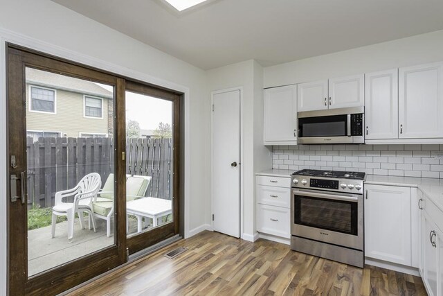 4140 Brentwood Ln, Waukegan, IL 60087 - kitchen featuring appliances with stainless steel finishes, light countertops, white cabinets, decorative backsplash, and wood finished floors