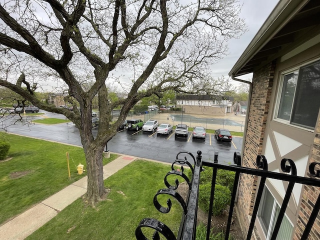surrounding community featuring uncovered parking, fence, and a yard