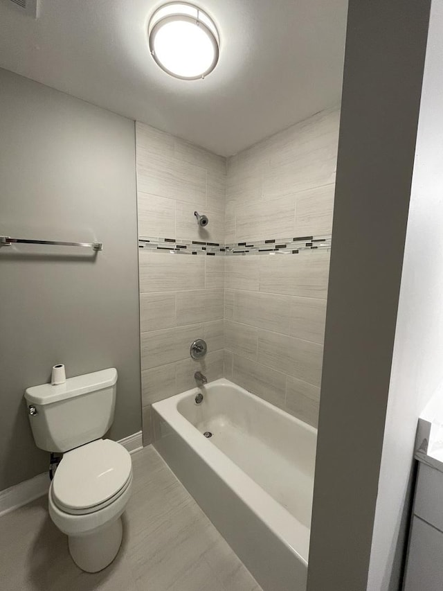 bathroom featuring baseboards, washtub / shower combination, tile patterned flooring, and toilet