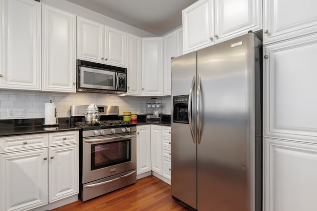 kitchen with dark countertops, decorative backsplash, stainless steel appliances, and white cabinetry