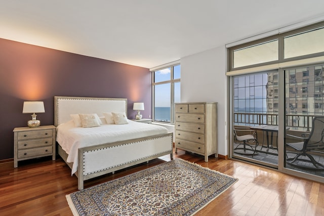 bedroom featuring a wall of windows, wood finished floors, and access to exterior