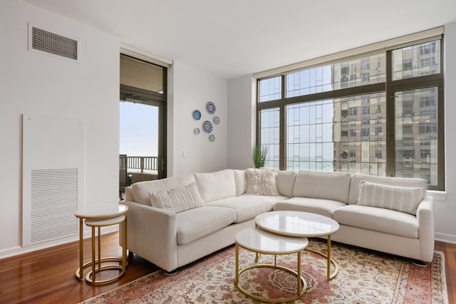 living room with a wall of windows, baseboards, wood finished floors, and visible vents