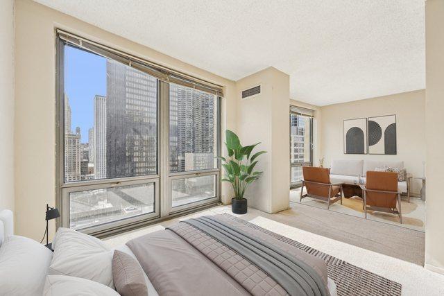 bedroom with a city view, a textured ceiling, and visible vents