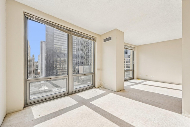 spare room with visible vents, carpet flooring, and a textured ceiling