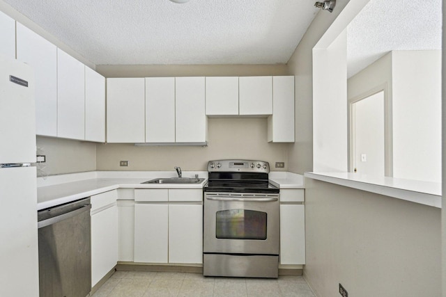 kitchen with light countertops, a textured ceiling, white cabinets, a sink, and appliances with stainless steel finishes