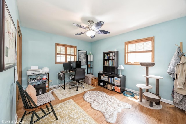office space with healthy amount of natural light, a ceiling fan, baseboards, and wood finished floors