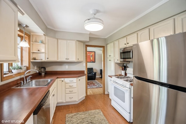 kitchen with stainless steel appliances, a sink, light wood finished floors, open shelves, and dark countertops