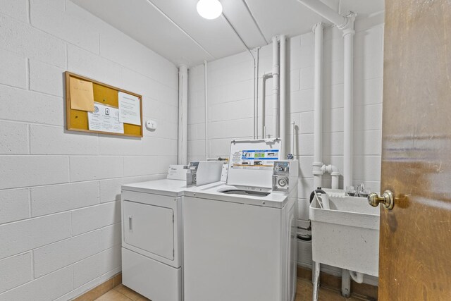 laundry area with a sink, concrete block wall, and independent washer and dryer