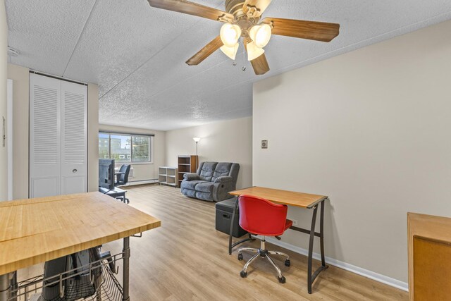 interior space with baseboards, a ceiling fan, light wood finished floors, and a textured ceiling
