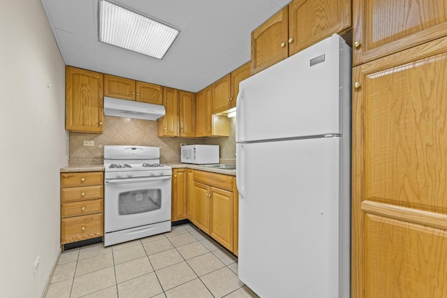 kitchen with light countertops, light tile patterned floors, under cabinet range hood, and white appliances