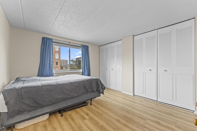 bedroom with two closets and light wood finished floors