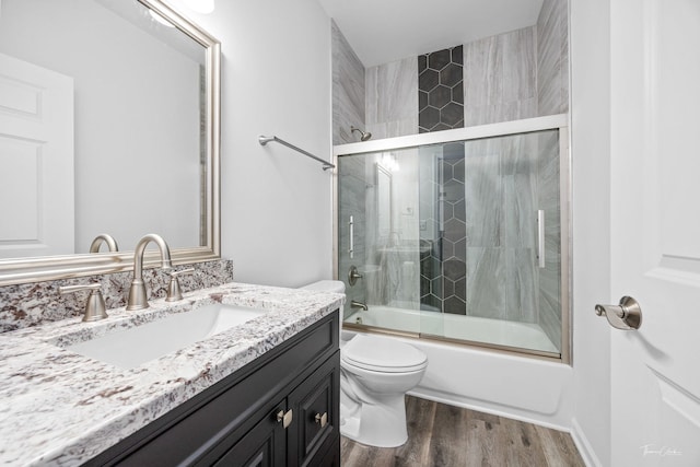 full bathroom featuring enclosed tub / shower combo, toilet, wood finished floors, and vanity