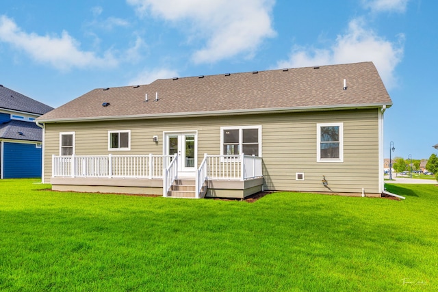 back of house with a deck, a yard, and a shingled roof