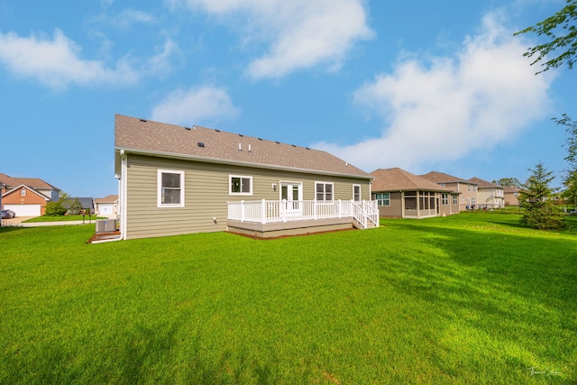 back of property featuring a wooden deck, a lawn, and a sunroom