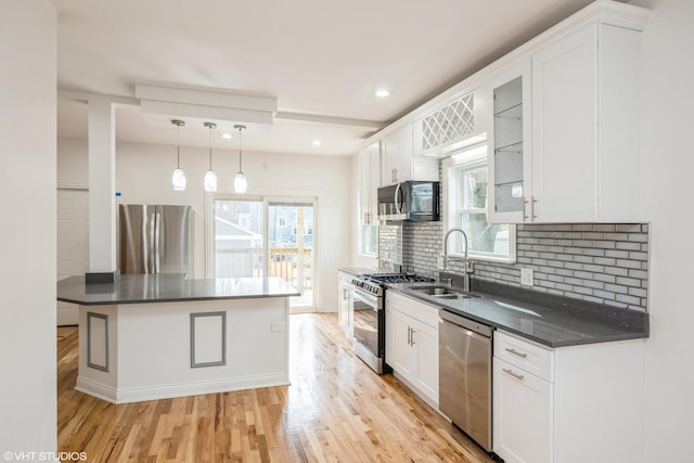 kitchen with dark countertops, light wood finished floors, appliances with stainless steel finishes, and a sink
