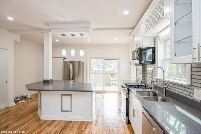 kitchen with light wood-style flooring, a sink, white cabinetry, decorative backsplash, and stainless steel appliances