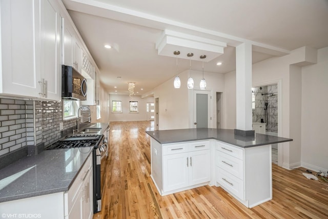 kitchen featuring a sink, white cabinetry, open floor plan, light wood-style floors, and appliances with stainless steel finishes