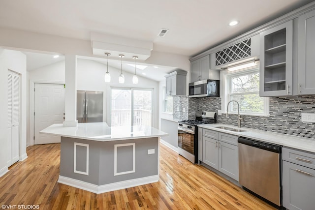 kitchen with a sink, stainless steel appliances, gray cabinetry, vaulted ceiling, and tasteful backsplash