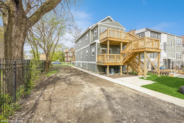 rear view of house featuring stairway, a wooden deck, and fence