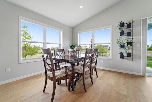dining room featuring baseboards, light wood finished floors, and vaulted ceiling