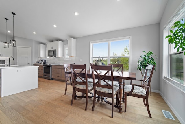 dining area with lofted ceiling, recessed lighting, light wood finished floors, and visible vents