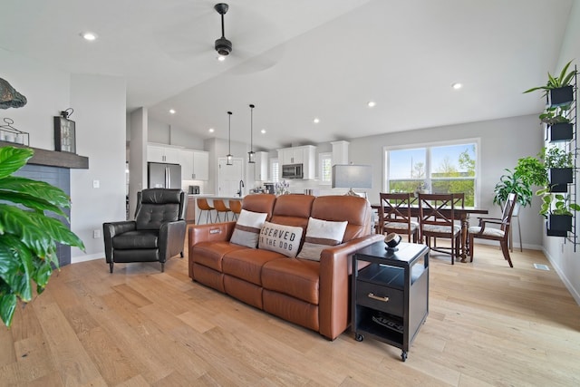 living room featuring a ceiling fan, baseboards, light wood-style floors, vaulted ceiling, and recessed lighting