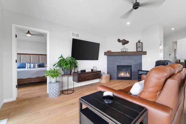 living area featuring visible vents, recessed lighting, light wood-style flooring, a ceiling fan, and a tiled fireplace