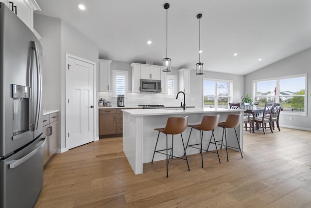 kitchen with light countertops, stainless steel appliances, light wood-style flooring, and a breakfast bar