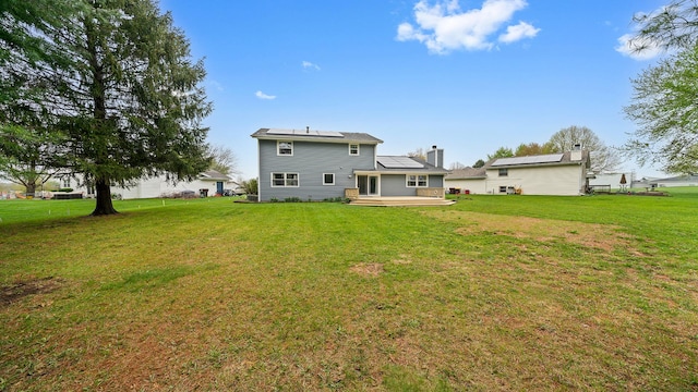 4401 Windsor Ct, Loves Park, IL 61111 - rear view of property featuring a lawn, a chimney, and solar panels