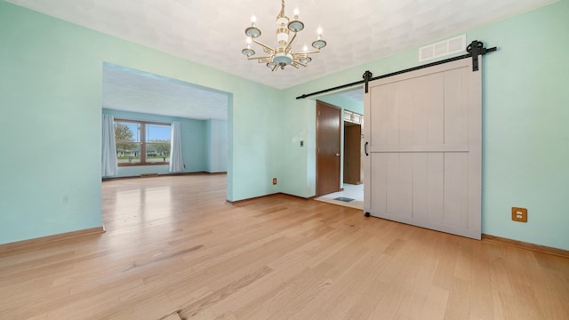 4401 Windsor Ct, Loves Park, IL 61111 - unfurnished dining area with visible vents, an inviting chandelier, baseboards, a barn door, and light wood-style flooring