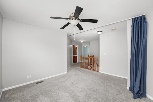 carpeted spare room featuring attic access, visible vents, baseboards, and ceiling fan